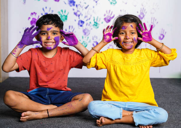Cheerful kids with messy colorful hands grimacing to camera at home - concept of mischievous, innocent and humor. Cheerful kids with messy colorful hands grimacing to camera at home - concept of mischievous, innocent and humor sibling relatonship  in kids stock pictures, royalty-free photos & images