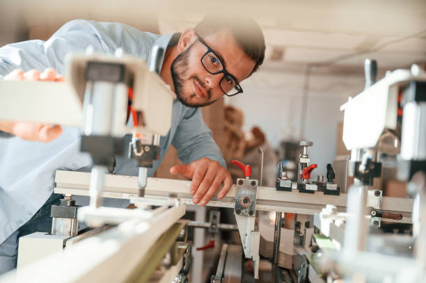 istock Using the cutting machine. Print house worker in white clothes is indoors 1457350701