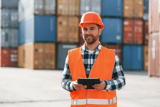 istock Standing with tablet in hands. Male worker is on the location with containers 1457352879