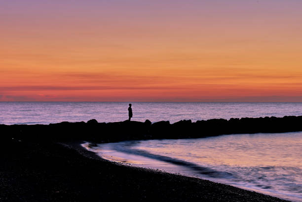 istock Silhouette of a child on a breakwater at dawn 1457352897