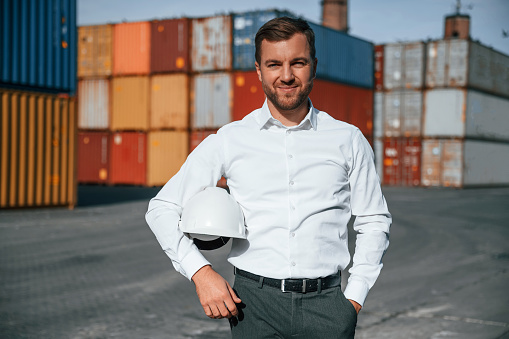 Beautiful portrait. Male worker is on the location with containers.
