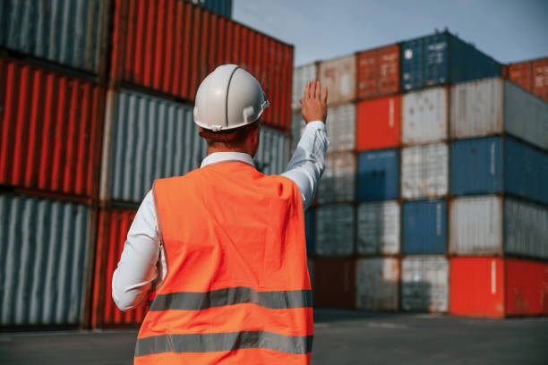 istock Rear view. Controlling the process. Male worker is on the location with containers 1457353526