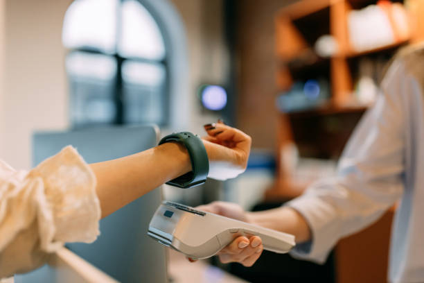 istock Female worker holding a paying machine, customer paying with a smart watch. 1457353983