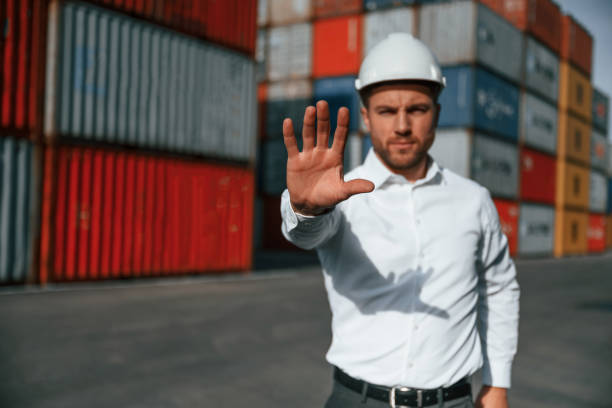 istock Stop, gesture. By the hand. Male worker is on the location with containers 1457354022