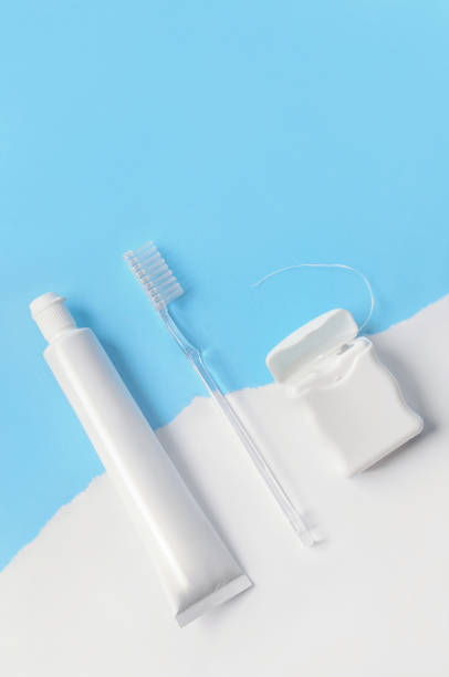 istock White toothbrush, dental floss and toothpaste on blue and white background selective focus copy space. 1457355526