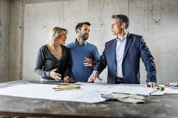 istock Happy couple talking to architect about blueprints at construction site. 1457355634