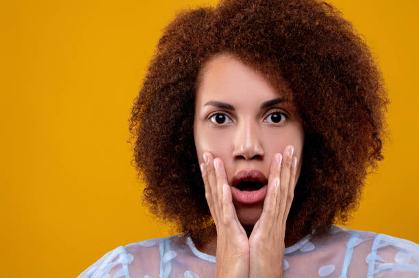 istock Pretty curly-haired woman in white blouse looking surprised 1457357302