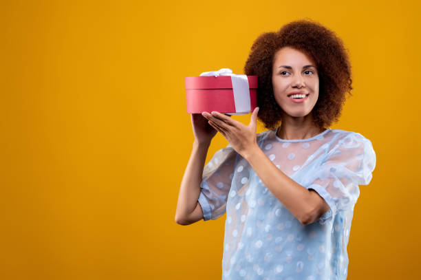 istock A young woman holding a gift box and looing happy 1457357571
