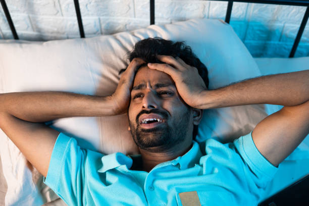 istock screaming young man suffering from sleeplessness or insomnia disorder at night on bedroom - concept of drug addict, migraine and stress 1457359093