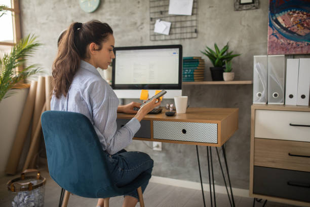 istock Mid adult woman using her smart phone while working from home 1457364752