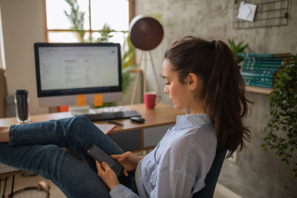 istock Mid adult woman using her smart phone while working from home 1457365255