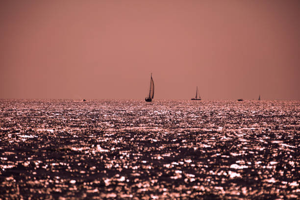 silhouette eines segelbootes bei sonnenuntergang sonnenaufgang und ozeanhorizont. - einige gegenstände mittelgroße ansammlung stock-fotos und bilder