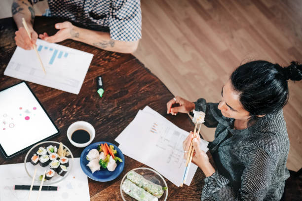 仕事場で昼休みを過ごすビジネスマン - two people business lunch multi ethnic group meeting ストックフォトと画像