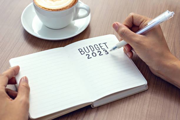 istock Businesswomen writing budget 2023 text on note pad for new year resolution plan. 1457373825