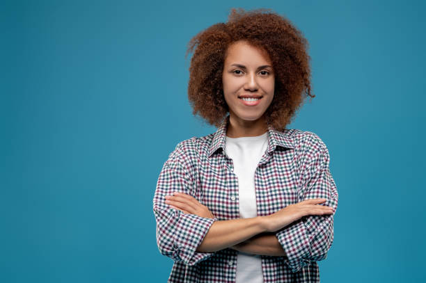 istock Confident curly-haired woman standing with the hands crossed 1457374962