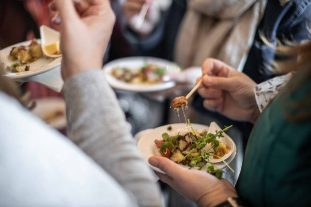 Guests enjoying the menu at a food festival in the Fall A group of people standing while they eat a tasty dish from a Fall food festival in Canada watercress stock pictures, royalty-free photos & images