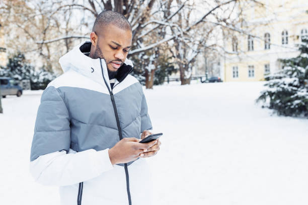 istock Young African man typing message, texting on phone, winter outdoor 1457377215