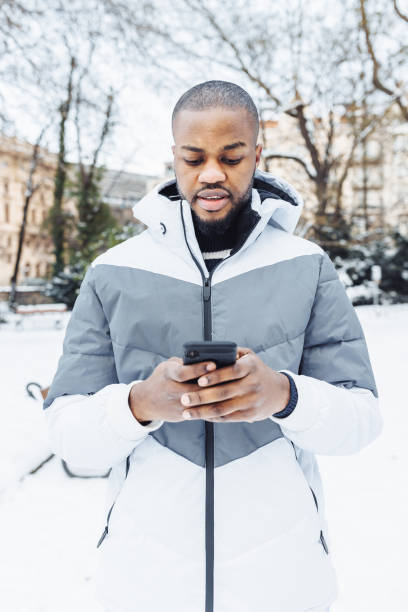 istock Young African man typing message, texting on phone, winter outdoor 1457377233