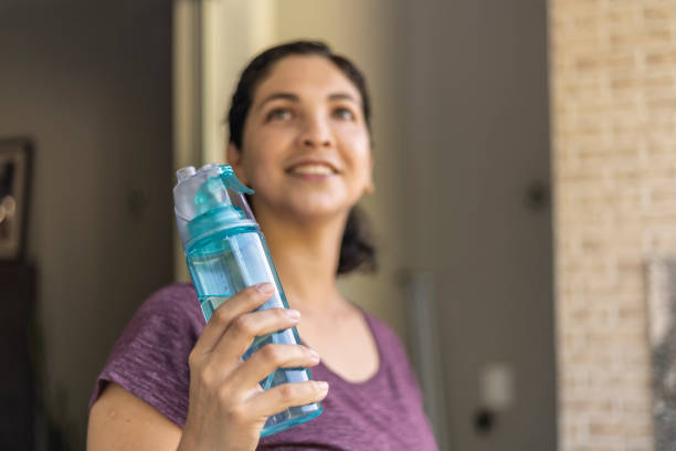 istock Latin woman drinking water from a green bottle 1457377344