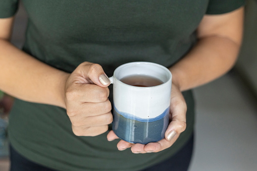 Female hands holding ceramic cup of tea