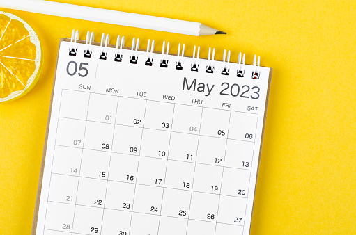 May 2023 Monthly desk calendar for 2023 year with wooden pencil on yellow background.