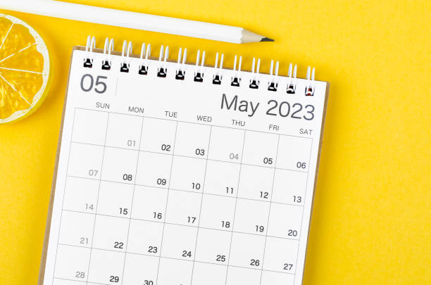 The May 2023 Monthly desk calendar for 2023 year with wooden pencil on yellow background. stock photo