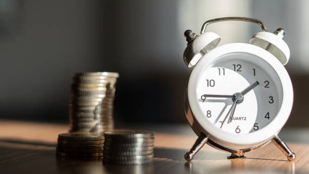 istock Coins and alarm clock on the table 1457380156
