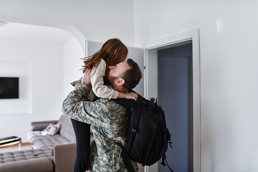 Military Officer Embracing And Lifting Daughter