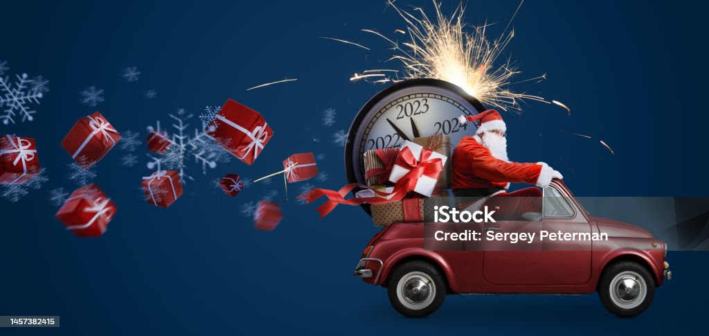 Santa Claus 2023 countdown on car Christmas is coming. Santa Claus on toy car delivering New Year 2023 gifts and countdown clock at blue background with fireworks 2023 Stock Photo