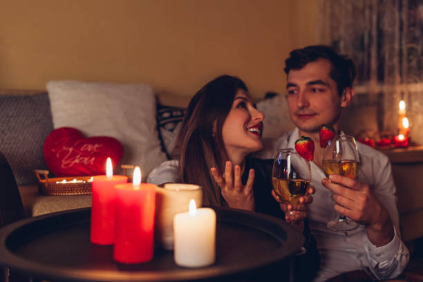 istock Valentines Day couple in love talking drinking wine with strawberries having romantic dinner celebrating at home 1457383335