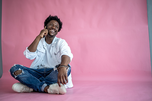 Young talking on the phone on a pink background