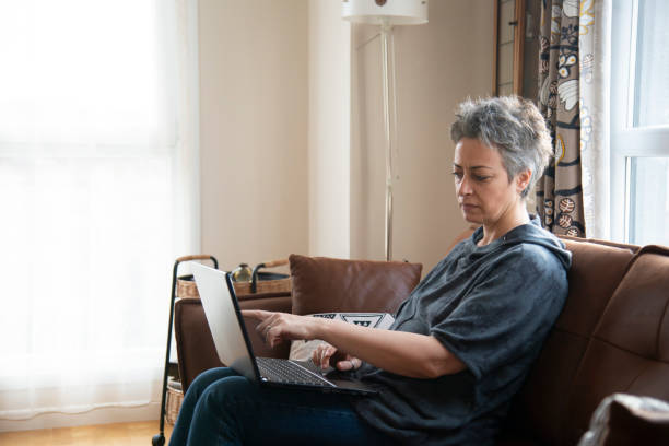 istock Beautiful woman sitting on sofa with laptop 1457387578