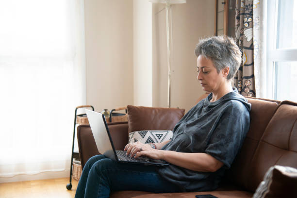 istock Beautiful woman sitting on sofa with laptop 1457387590