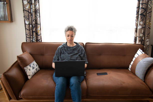 istock Beautiful woman sitting on sofa with laptop 1457388397
