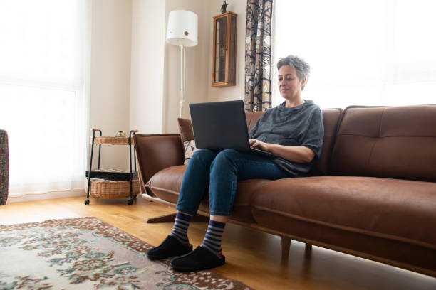 istock Beautiful woman sitting on sofa with laptop 1457389188