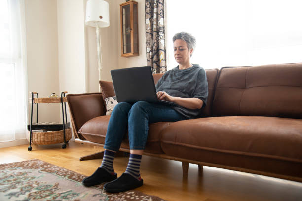 istock Beautiful woman sitting on sofa with laptop 1457389189