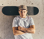Skateboard, fashion or man with arms crossed in city skate park for stunt training, hobby exercise or freestyle skating in top view. Portrait, skater or skateboarder lying on concrete ground or floor