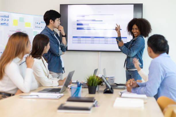 istock Professional marketer is making a presentation during a planning business meeting with colleagues. Meeting of diverse young entrepreneurs, talking, Businesspeople develop startup. 1457390192
