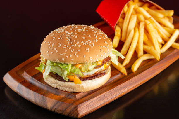 istock Delicious hamburger with two meats, cheddar cheese, fried egg, sauce and salad. Accompanied by french fries. 1457391027