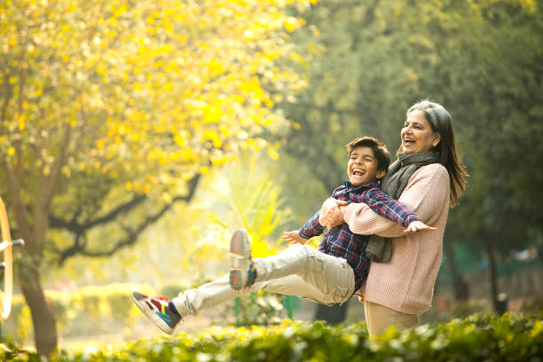 Cheerful grandmother playing with grandson at park Happy grandmother spending leisure time together at park indian ethnicity lifestyle stock pictures, royalty-free photos & images