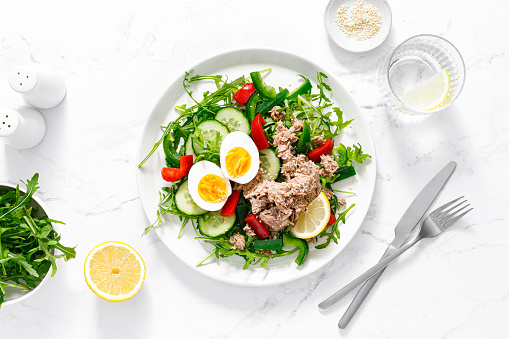 Salad with canned tuna, boiled egg, arugula and fresh vegetables. Top view