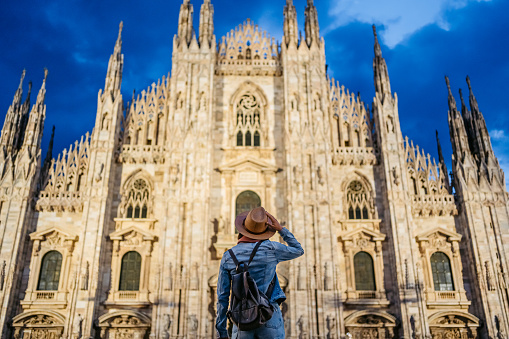 Beautiful young female tourist enjoying the view of the cathedral in Milan, Italy at night.