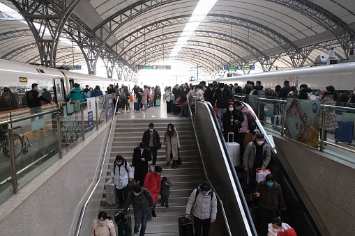 Wuhan,China-Jan.18th 2023: many Chinese passengers in face mask to prevent covid-19, walking in Hankou railway station during Spring Festival travel rush