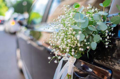 Close up of luxury wedding car flowers decoration. Nuptial event. Beautiful gypsophila white green flowers.