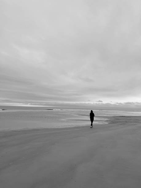 istock Person Walking on Beach Black and White 1457403940