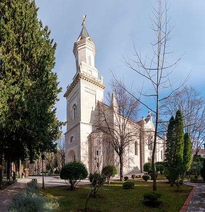 The Orthodox Church of The Holy Transfiguration of God also known as Crkva Preobraenja Gospodnjeg with tall belltower and green park trees and lawn angle view