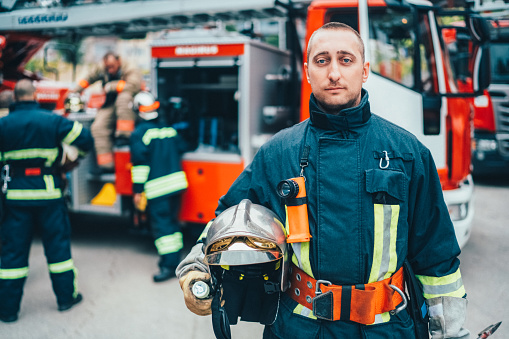 Firefighter with work helmet under arm looking at camera