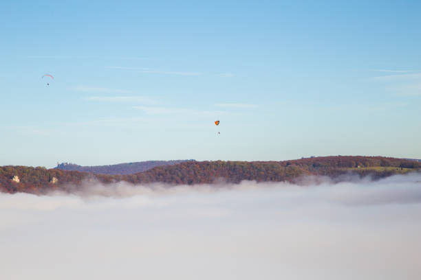 Paragliders are above the clouds.