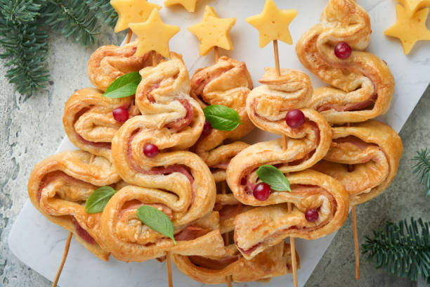 istock Christmas or New Year appetizer. Christmas tree shape puff pastry buns with cheese and ham. Group of Christmas tree shapes on marble stand. Festive idea for Christmas or New Year dinner. Top view. 1457406985