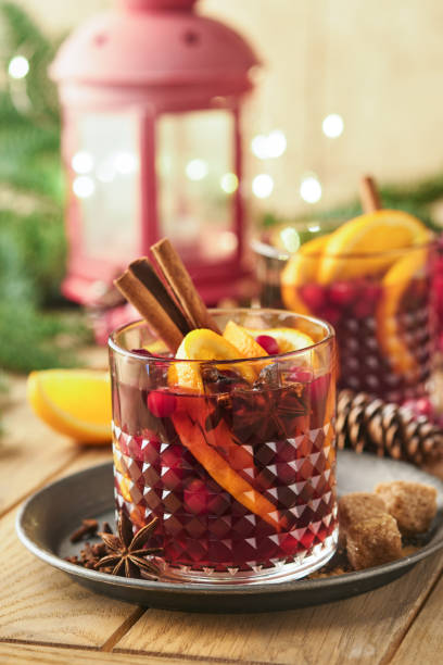 Christmas hot mulled wine. Glasses of mulled wine with aromatic spices cinnamon, anise, sugar and fir tree branches with bokeh and decorations. Traditional Xmas festive drink. Winter Christmas drink. stock photo